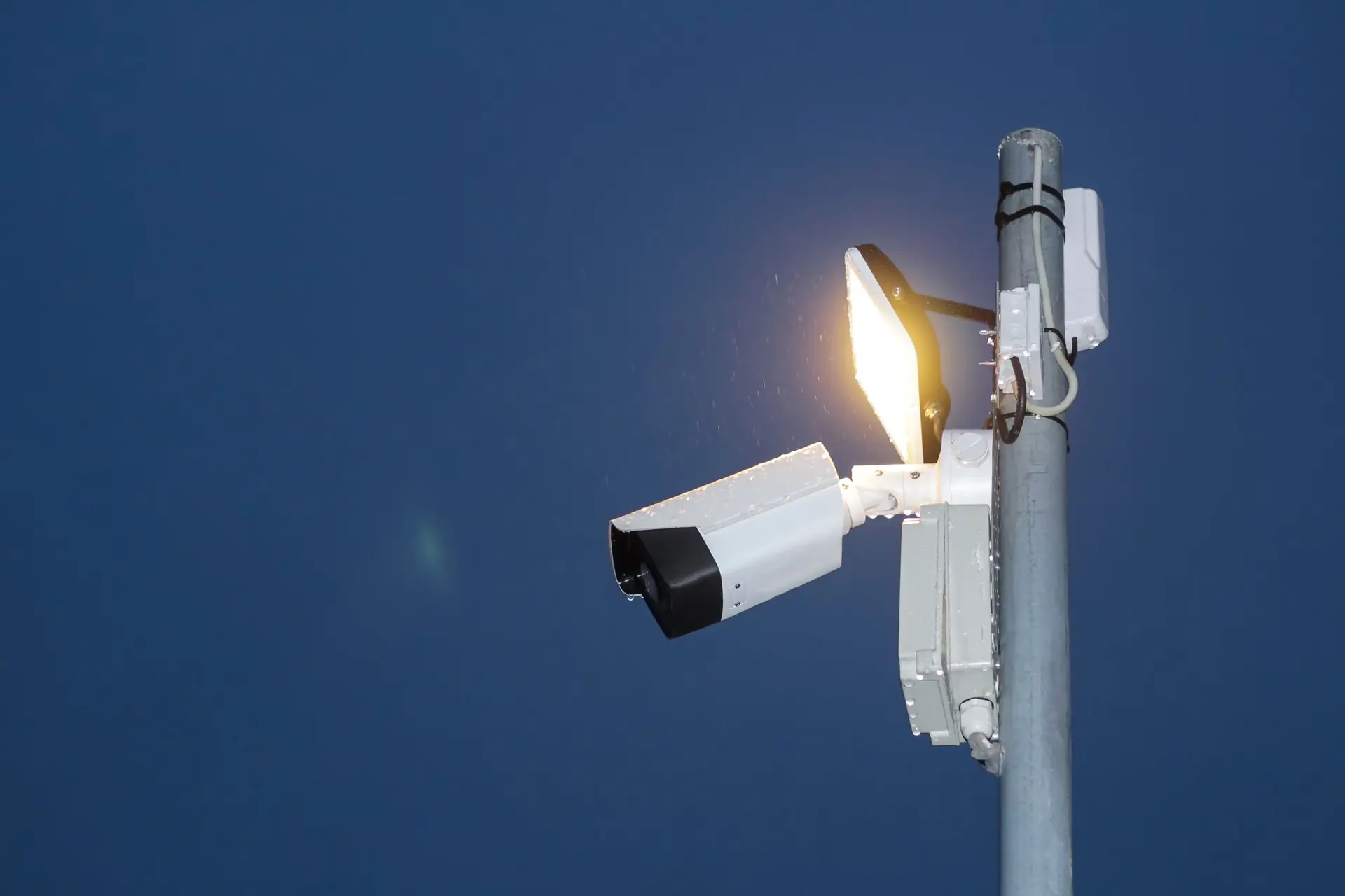Surveillance camera and floodlight on a pole at night