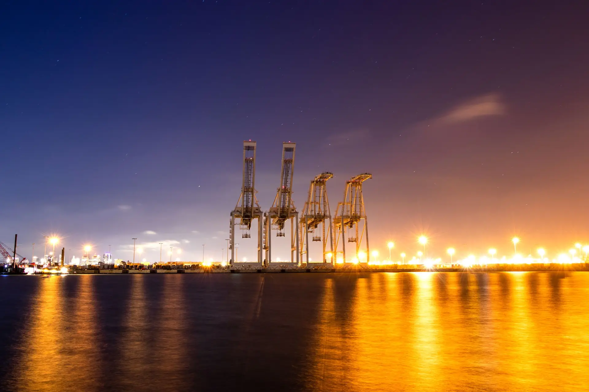 Container cranes lit at night along a commercial port